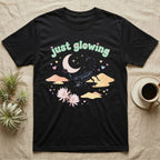 Emperor Scorpion Baby T-Shirt in Black — Black emperor scorpion, pincers raised, under a pastel moon and stars with puffy mint bubble text "just glowing".