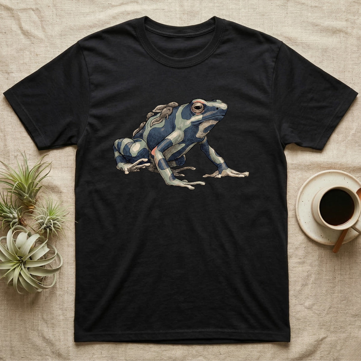Dart Frog Tadpole T-Shirt in Black — Naturalist-plate illustration of a dyeing dart frog carrying tadpoles on its back with a dry typewriter caption beside it.
