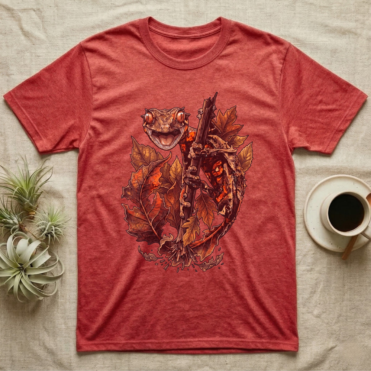 Satanic Leaf-Tailed Gecko Autumn T-Shirt in Heather Red — Painted illustration of a satanic leaf-tailed gecko gripping a bare stem among dried autumn leaves in rust and amber, no on-shirt text.