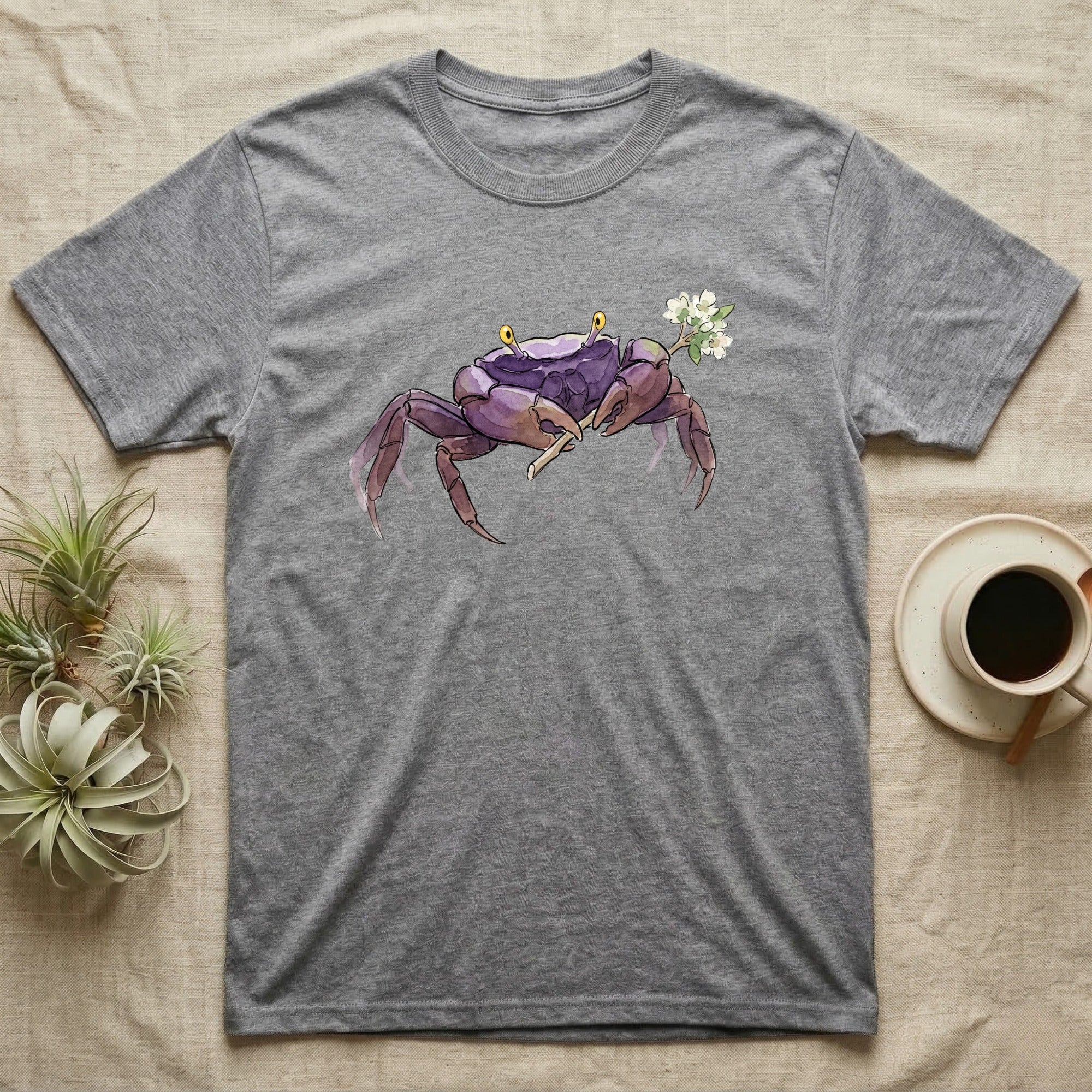 Vampire Crab Blossom T-Shirt in Sport Grey — Watercolor illustration of a violet-purple vampire crab with yellow eye stalks holding a moss-flower blossom sprig, on a dark grey t-shirt.