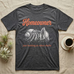 Hermit Crab Homeowner T-Shirt in Dark Heather — White-line engraving of a land hermit crab eyeing a bigger empty shell, under orange script Homeowner and a serif line