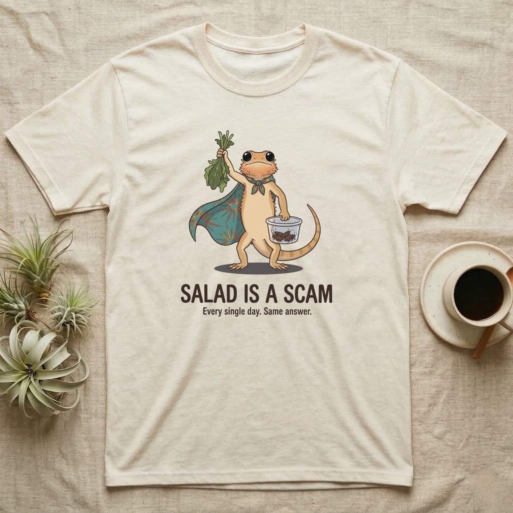 Bearded Dragon Salad Scam T-Shirt in Natural — Storybook-cartoon bearded dragon holding wilted greens at arm's length and a tub of roaches, captioned "Salad Is a Scam".