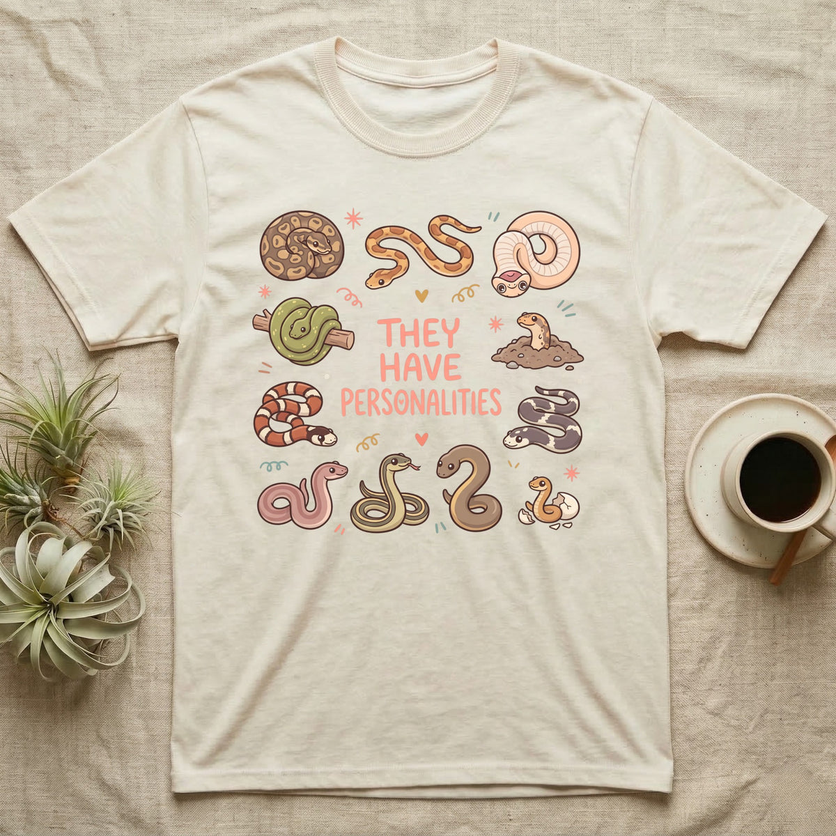 Snake Keeper Personalities T-Shirt in Natural — Outline illustration of five snakes in different postures scattered around hand-lettered script on grey.