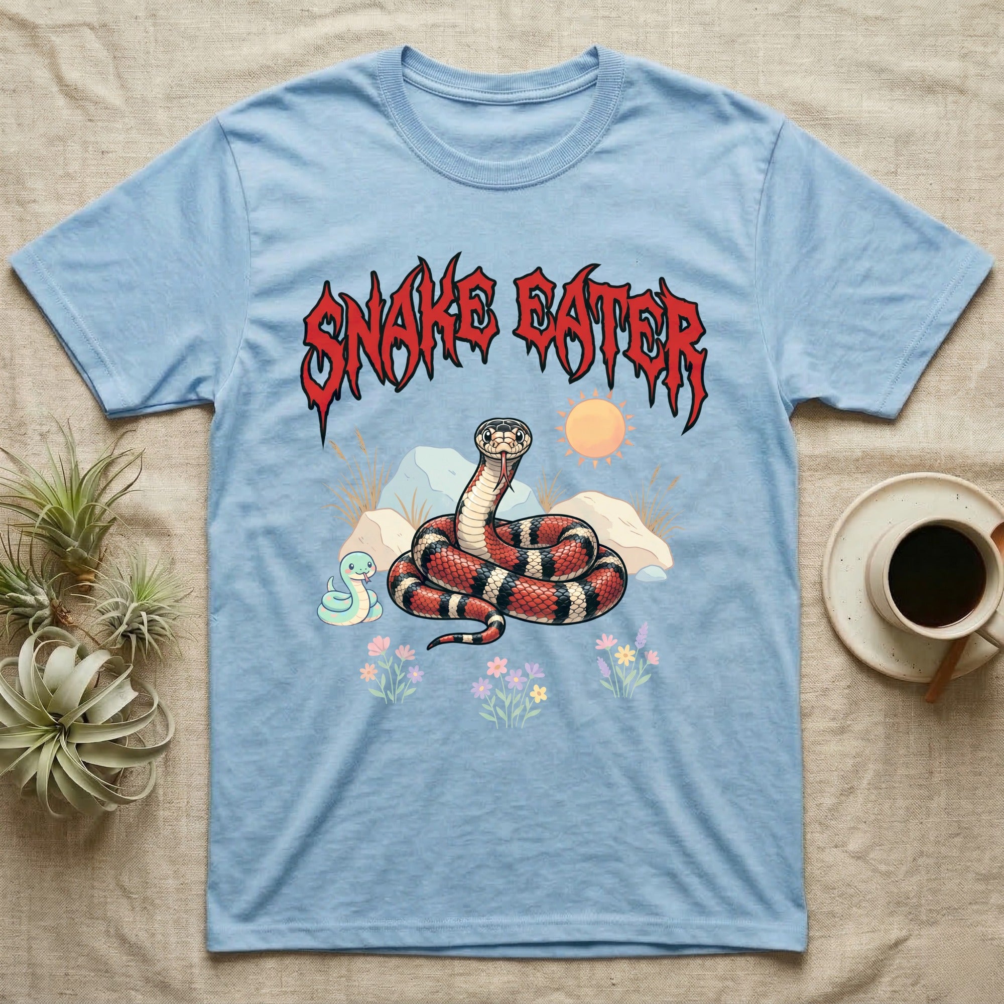 California Kingsnake Feral T-Shirt in Light Blue — Banded California kingsnake coiled with a tiny companion snake under a jagged blood-red metal wordmark and pastel scene.
