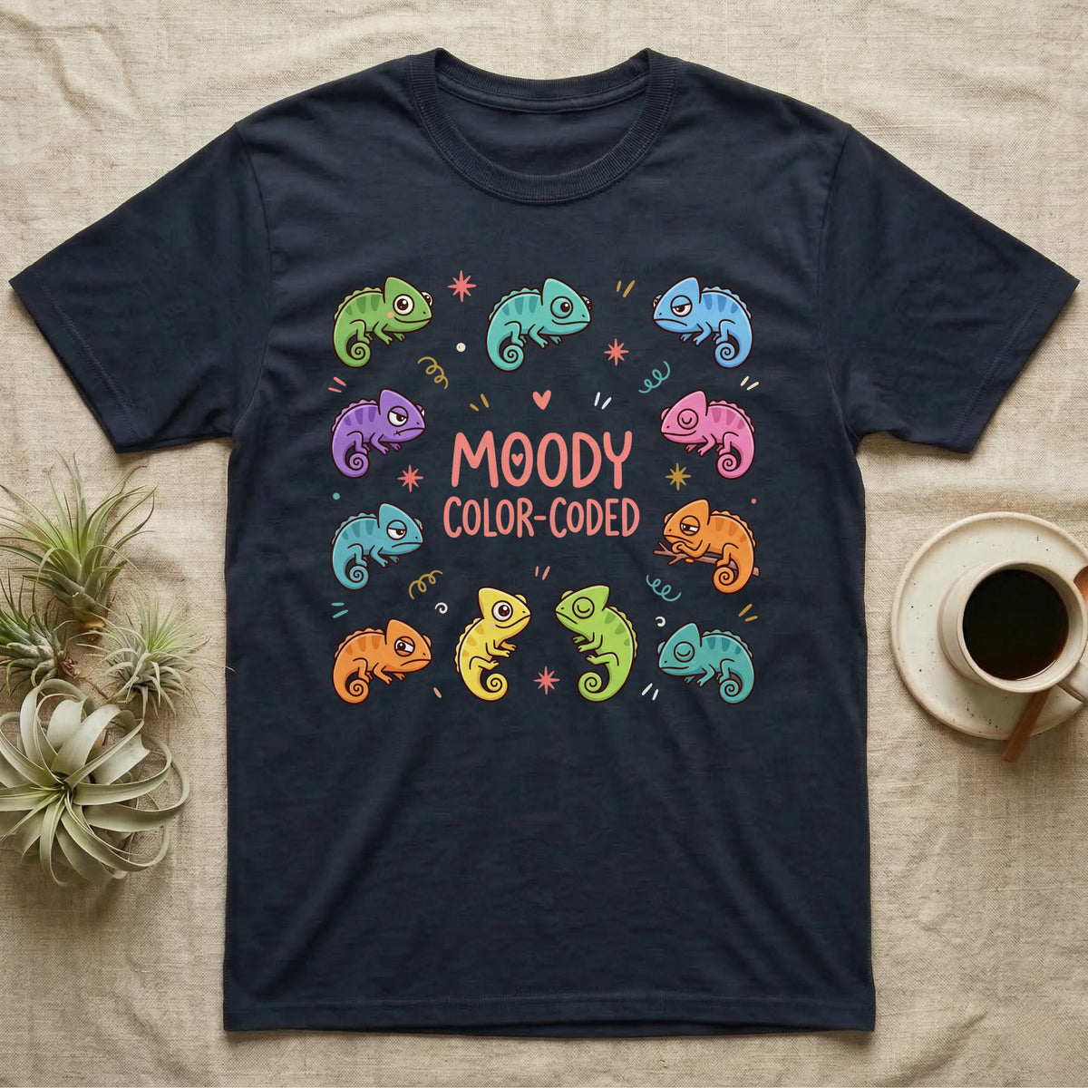 Chameleon Moody T-Shirt in Navy — Ten cartoon chameleons in different colours and moods around the coral-pink words MOODY COLOR-CODED