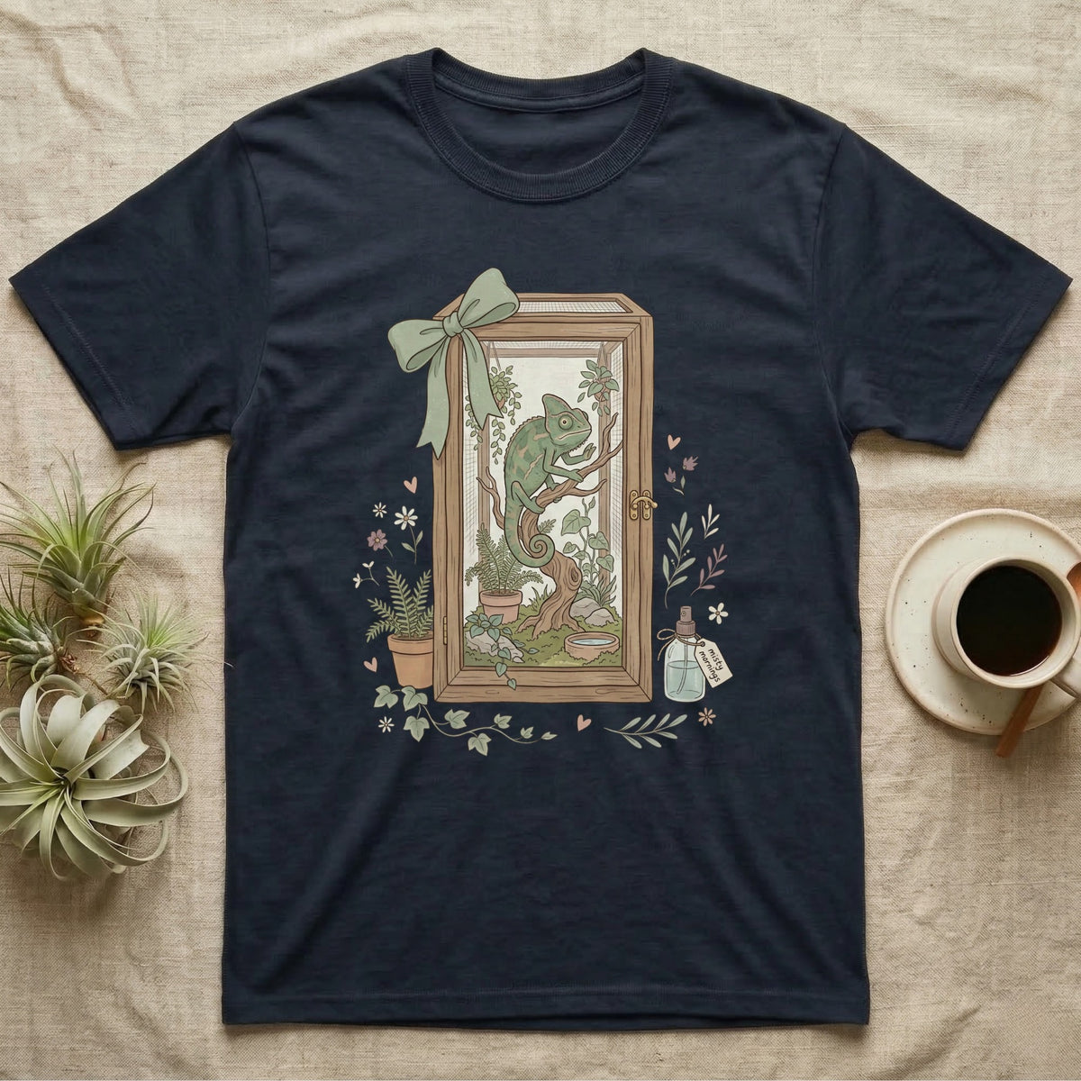 Chameleon in terrarium design on a navy t-shirt, with plants and a gift ribbon.
