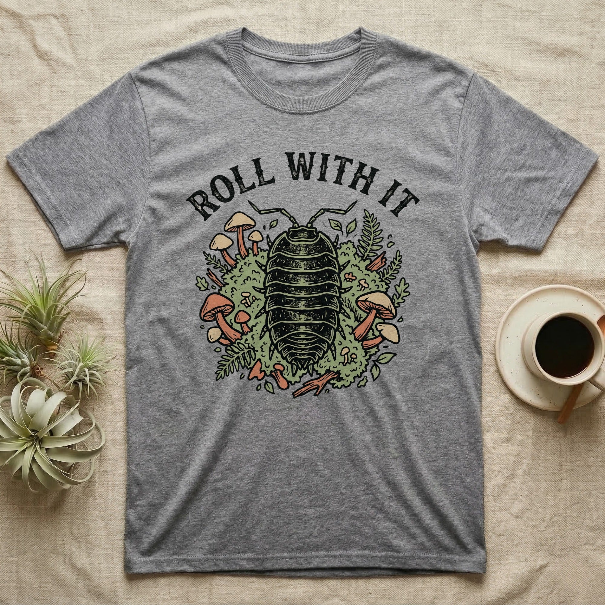 Gray t-shirt with "Roll With It" text and an illustration of an armadillo surrounded by mushrooms and plants.