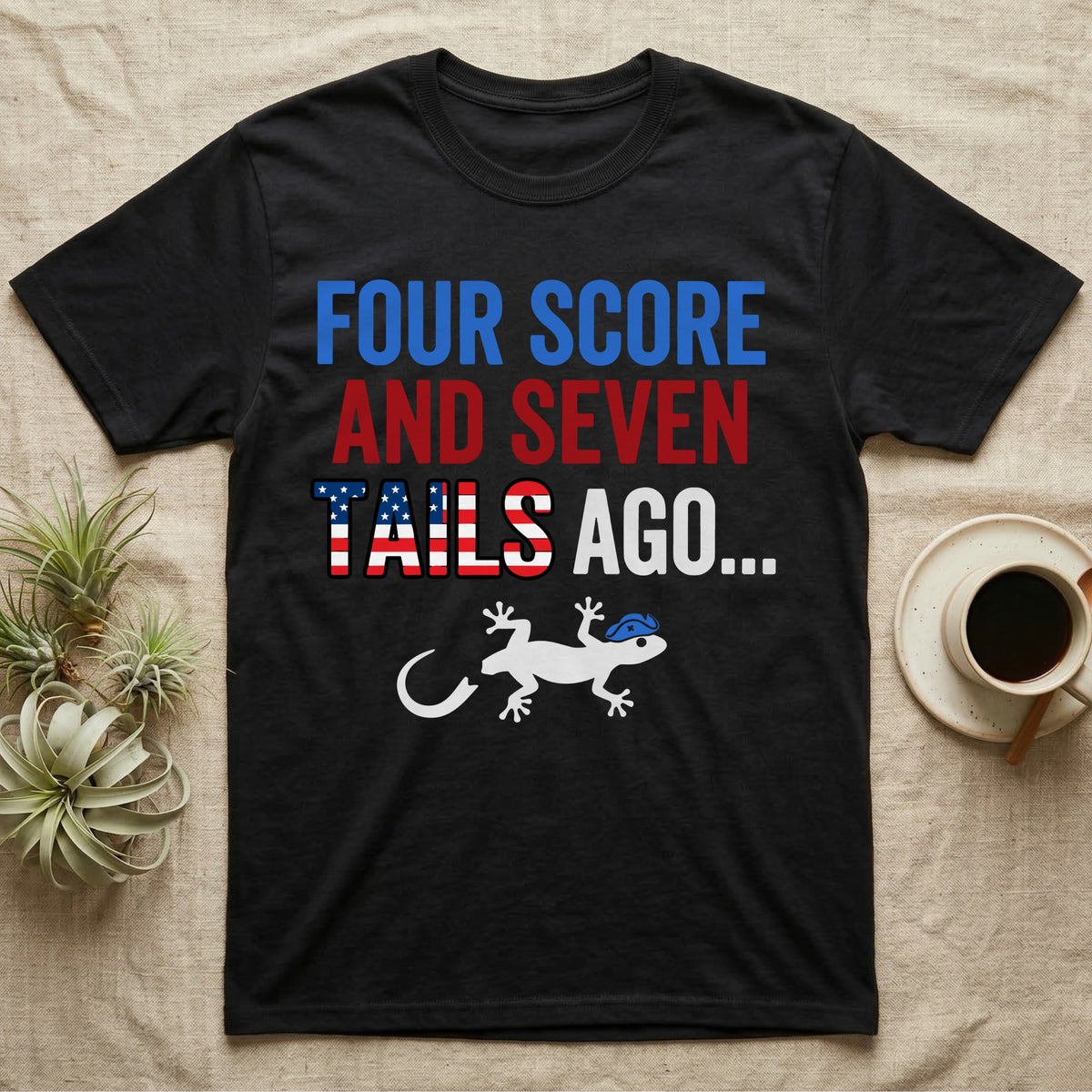 Gecko Four Score T-Shirt in Black — Block text Four Score and Seven Tails Ago with a flag-filled word above a white gecko silhouette shedding its tail.