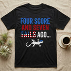 Gecko Four Score T-Shirt in Black — Block text Four Score and Seven Tails Ago with a flag-filled word above a white gecko silhouette shedding its tail.