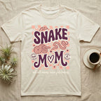 Cream t-shirt with "Snake Mom" design featuring snakes, hearts, and checkerboard pattern.