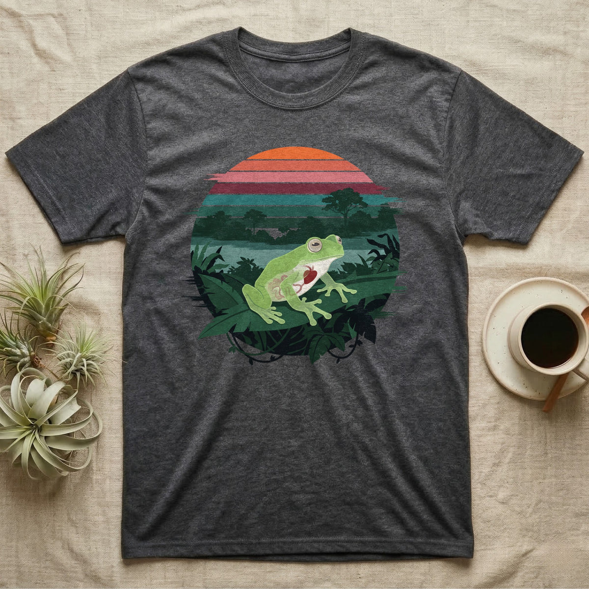 Glass Frog See-Through T-Shirt in Dark Heather — Flat-colour circle-window illustration of a glass frog silhouetted crossing a rainforest canopy scene.