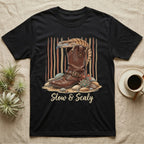 Black t-shirt with boot, lizard, succulents, and text "Slow & Scaly".