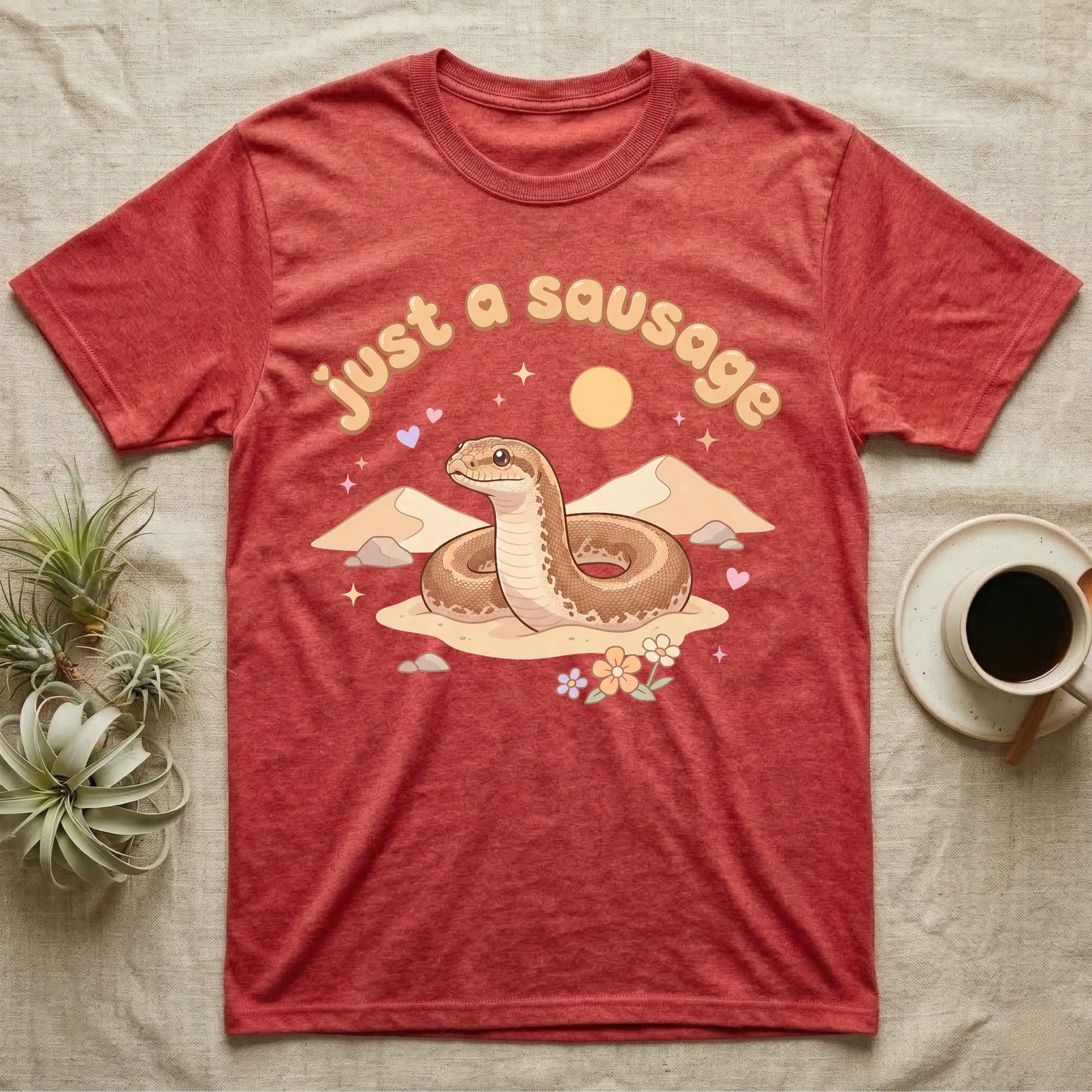 Kenyan Sand Boa Softie T-Shirt in Heather Red — Kenyan sand boa looping out of pastel sand dunes under a puffy "just a sausage" bubble wordmark with tiny hearts.