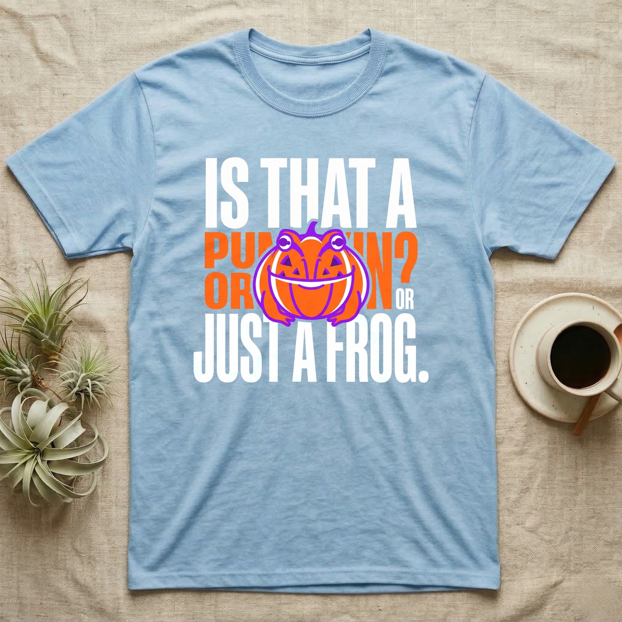 Frog Jack-O'-Lantern Illusion T-Shirt in Light Blue — Typographic graphic of an orange frog doubling as a jack-o'-lantern, "Is That a Pumpkin? Or Just a Frog."