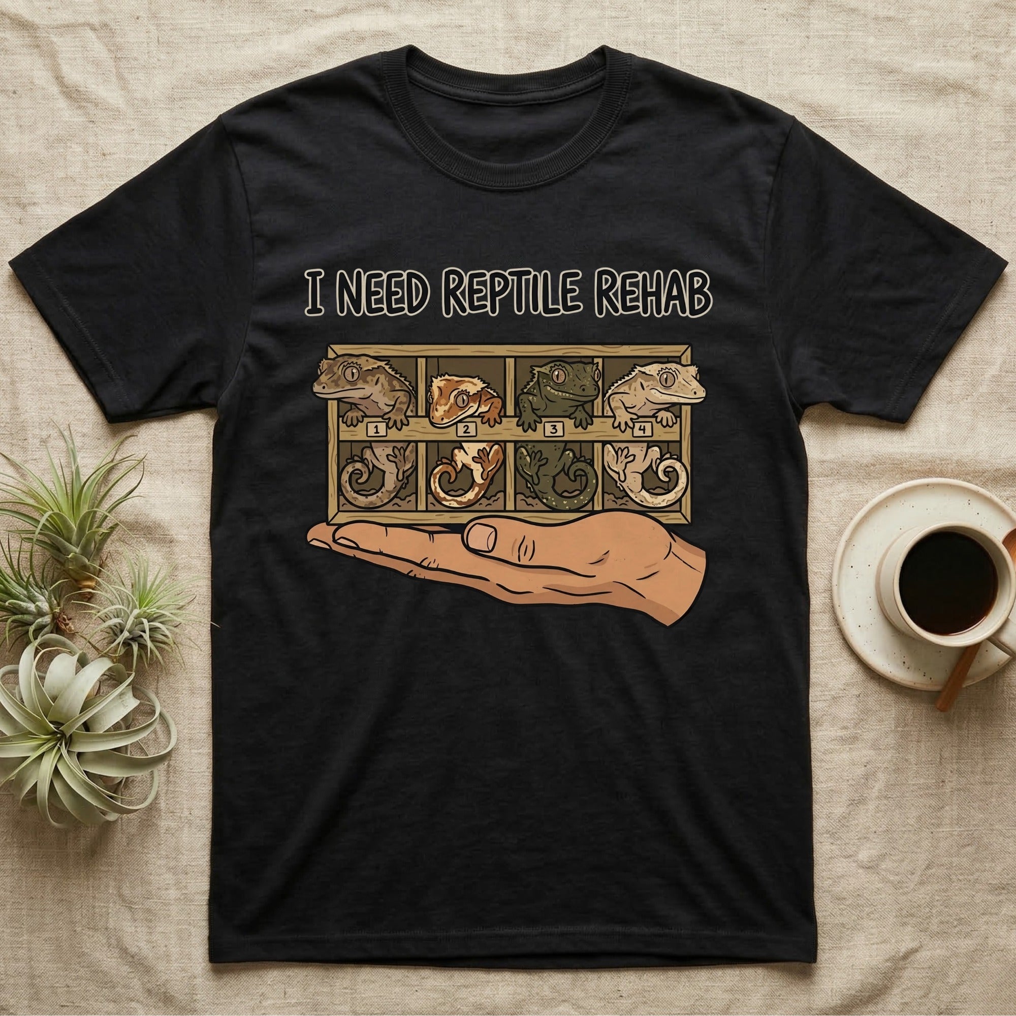 Crested Gecko Rehab T-Shirt in Black — Vector scene of a hand presenting a rack of four crested geckos under a marker-style reptile rehab caption.