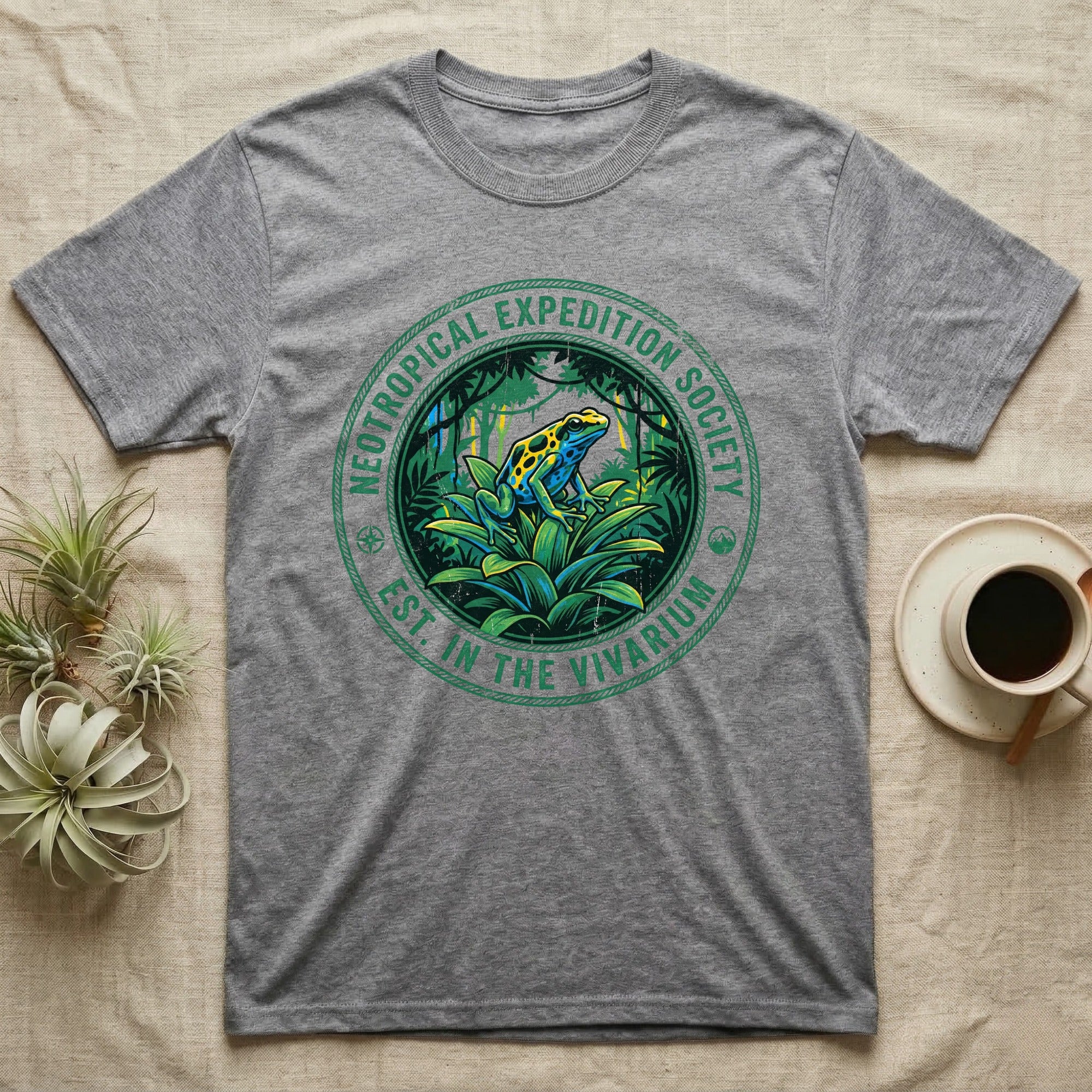 Grey t-shirt with green circular logo featuring a frog in a rainforest.