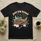 Burmese Python Baby T-Shirt in Black — Massive coiled Burmese python among pastel ferns and orchids under puffy butterscotch bubble text "just big boned".