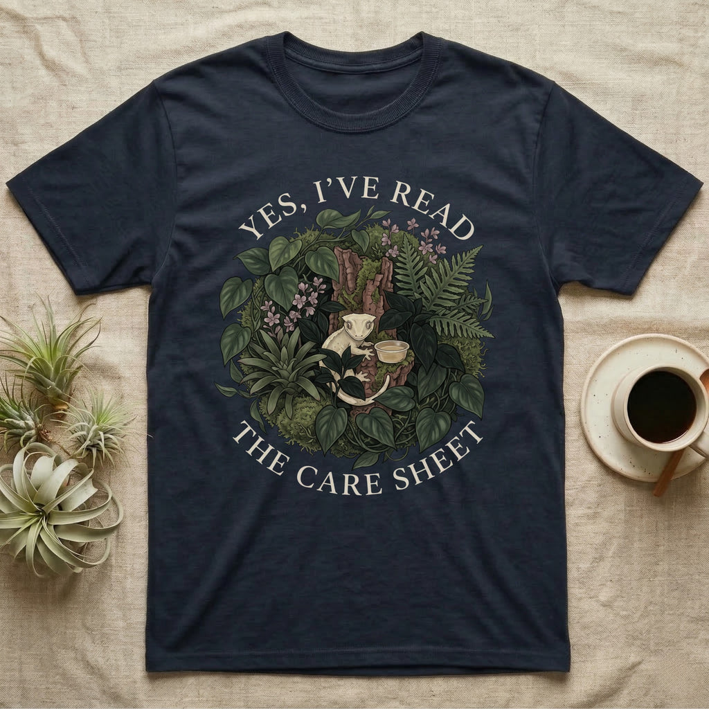 Crested Gecko Care Sheet T-Shirt in Navy — Botanical wreath of pothos and moss circling a crested gecko, closed by two arcs of Roman capitals.
