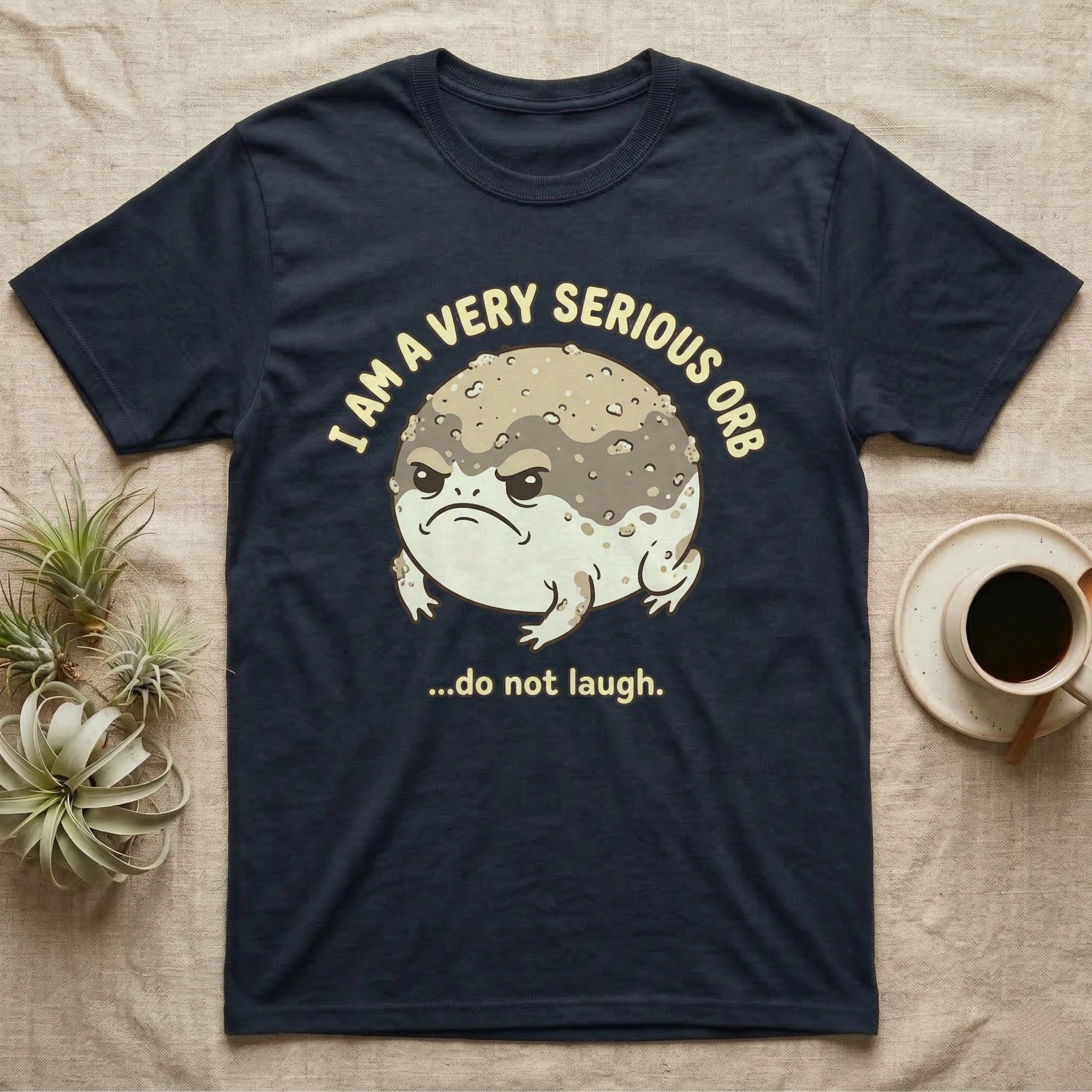 Dark t-shirt with a grumpy toad illustration and text "I am a very serious orb ...do not laugh."