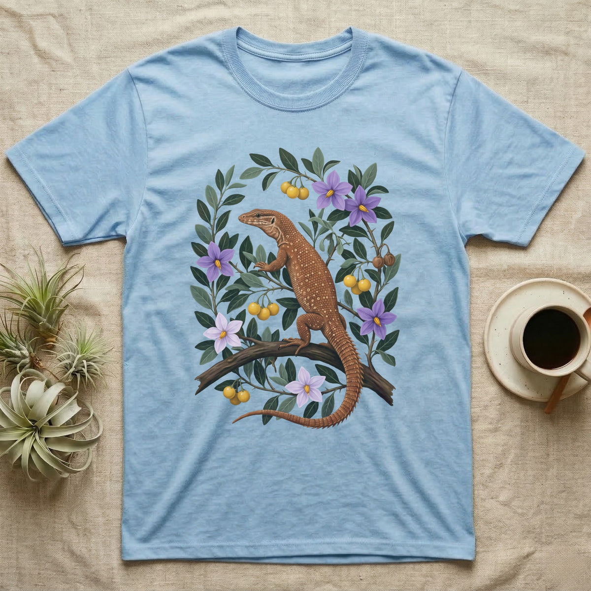 Ackie Monitor Botanical T-Shirt in Light Blue — Naturalist oil painting of a red ackie monitor on a branch inside an oval bower of bush tomato with violet flowers and yellow fruit.