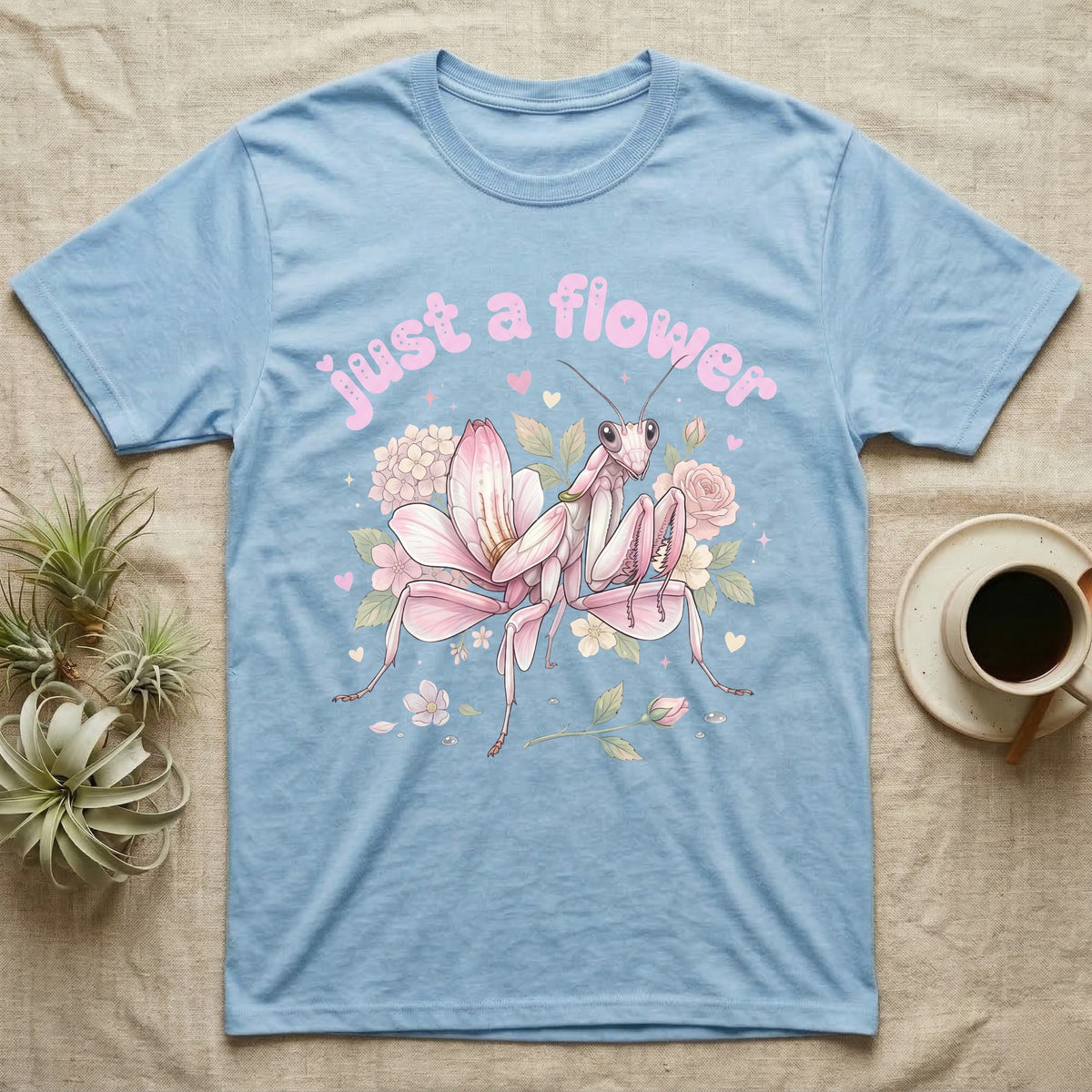 Orchid Mantis Softie T-Shirt in Light Blue — Pink orchid mantis mimicking a flower under pastel bubble text "just a flower" with tiny hearts.