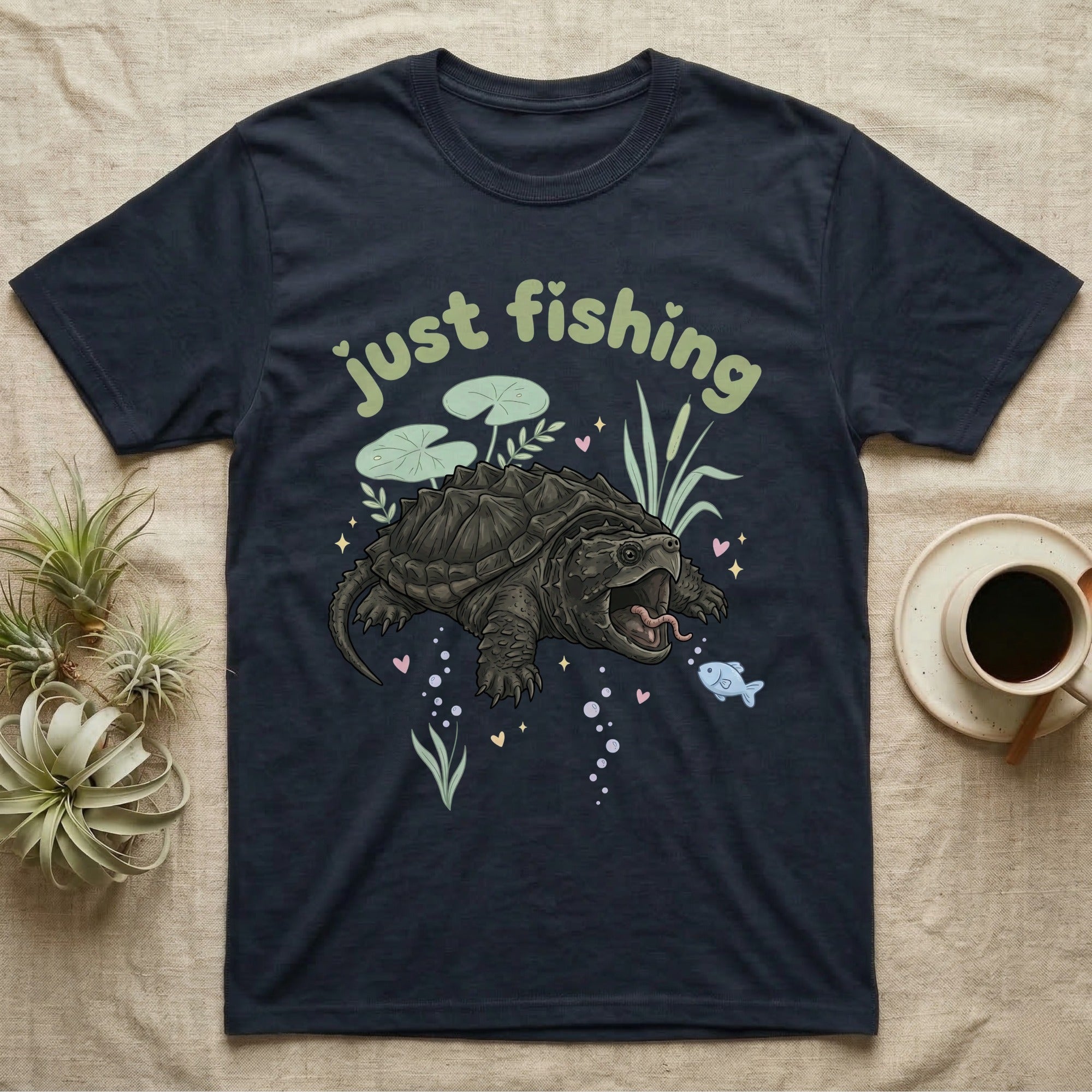 Alligator Snapping Turtle Softie T-Shirt in Navy — Alligator snapping turtle with open mouth and tongue lure under a puffy pastel "just fishing" bubble wordmark.