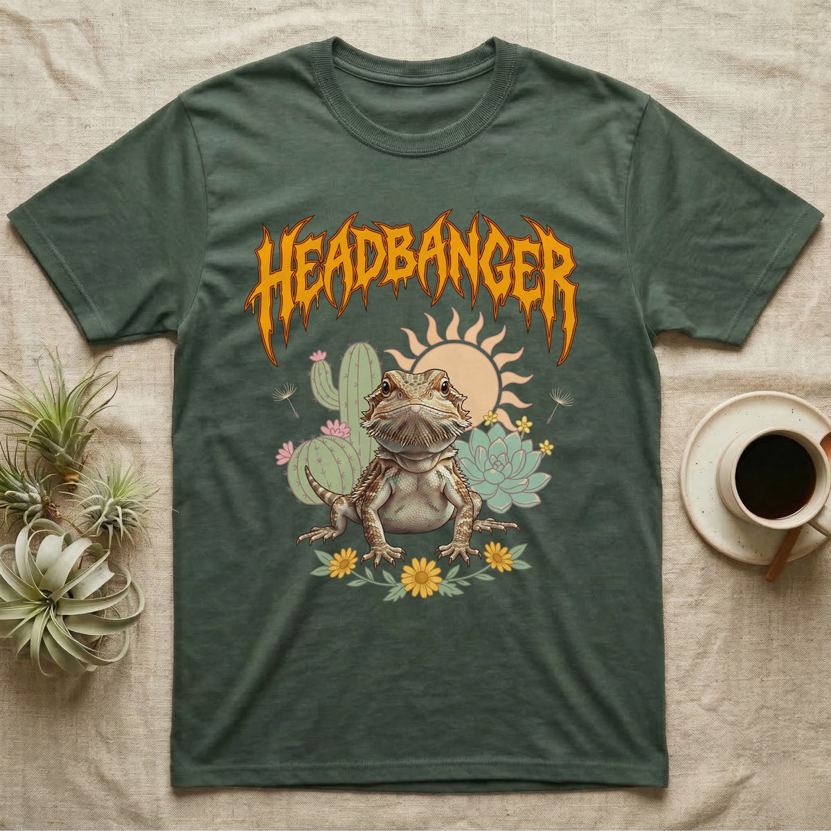 Central Bearded Dragon Feral T-Shirt in Military Green — Baby bearded dragon in a pastel desert scene under a spiky amber metal wordmark reading HEADBANGER.