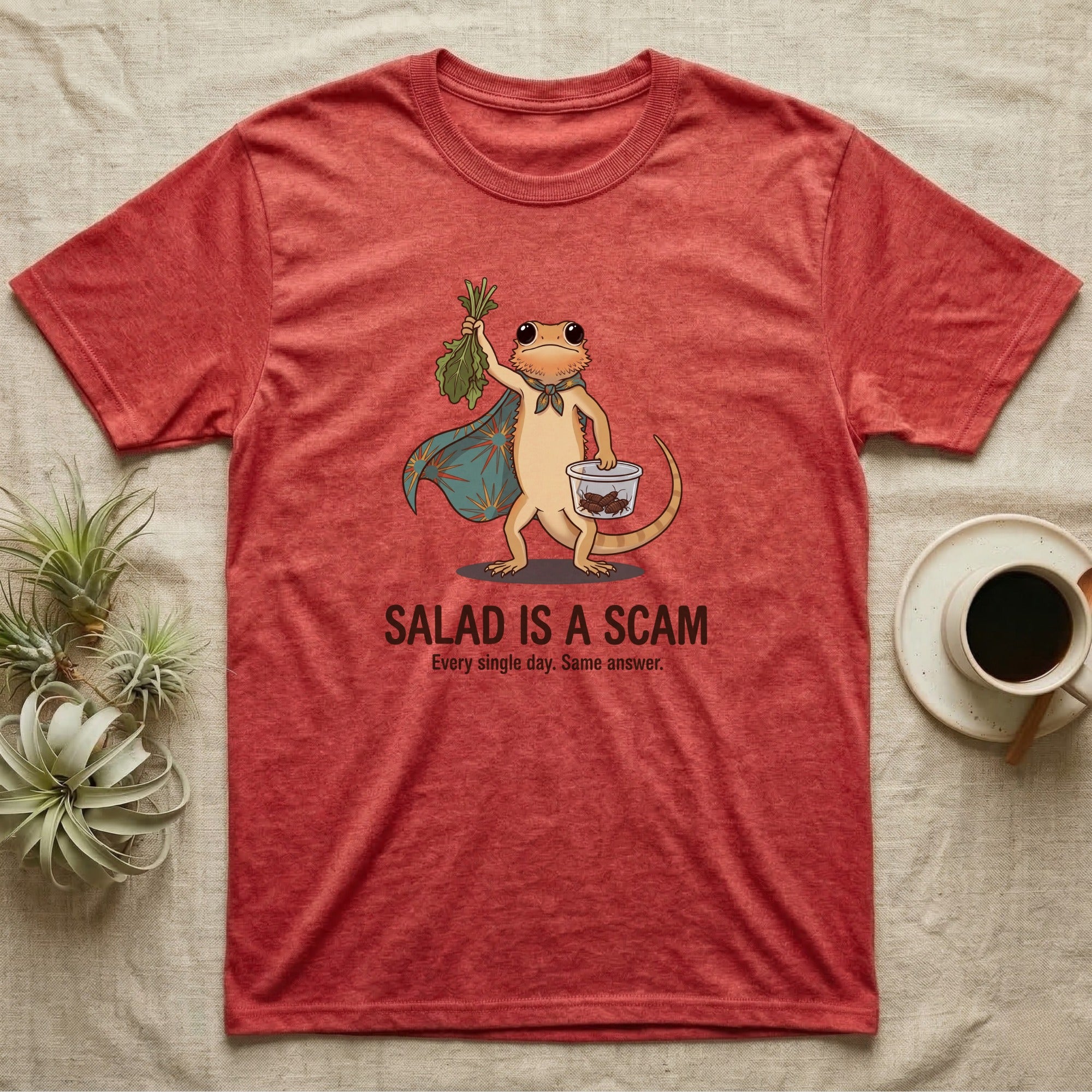Bearded Dragon Salad Scam T-Shirt in Heather Red — Storybook-cartoon bearded dragon holding wilted greens at arm's length and a tub of roaches, captioned "Salad Is a Scam".
