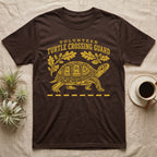 Box Turtle Crossing T-Shirt in Dark Chocolate — Yellow folk-print eastern box turtle walking across a dashed road line with oak leaves, text Volunteer Turtle Crossing Guard