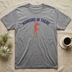 Crested Gecko Hanging T-Shirt in Sport Grey — Red crested gecko hanging by its front feet from the navy arched words HANGING IN THERE