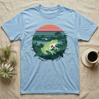 Glass Frog See-Through T-Shirt in Light Blue — Flat-colour circle-window illustration of a glass frog silhouetted crossing a rainforest canopy scene.