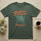 African Bullfrog Sun Lounger T-Shirt in Military Green — Illustrated African bullfrog reclining in a beach chair with sunglasses and a cocktail, retro coral script reading My Humour Is Naturally Hungry.