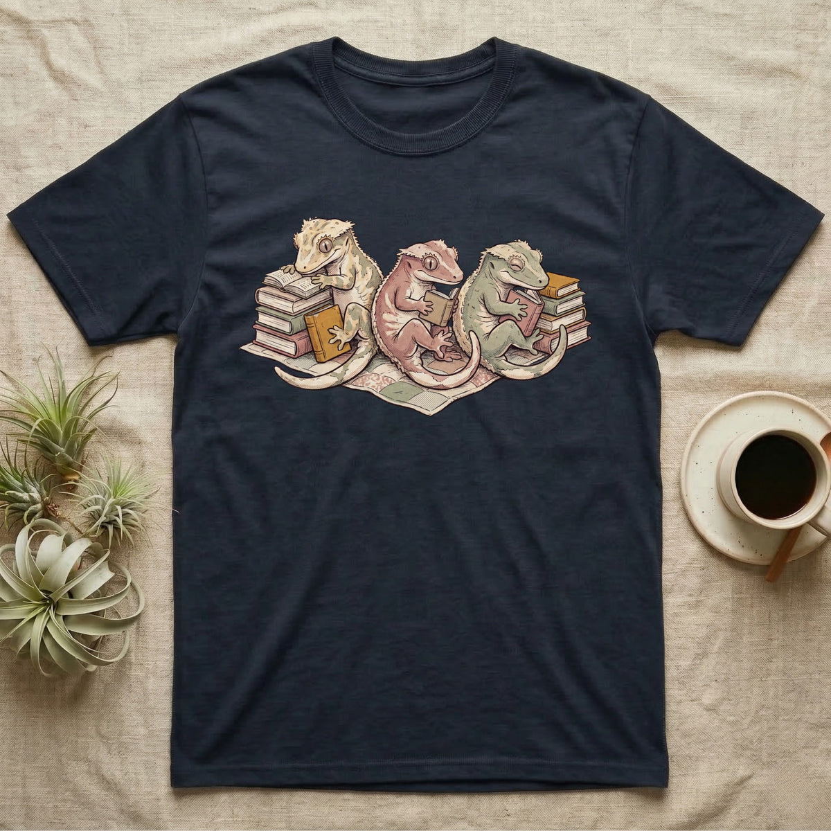 Gecko Book Club T-Shirt in Navy — Warm storybook illustration of three crested geckos in a cozy reading row, each beside a tiny stack of books.