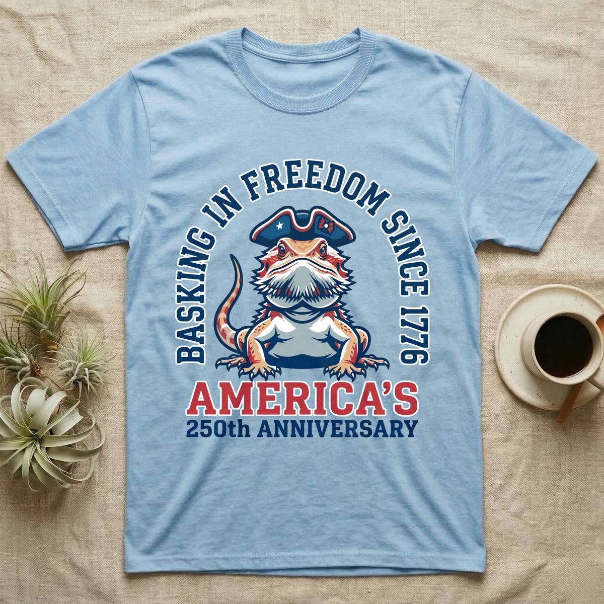 Bearded Dragon Basking T-Shirt in Light Blue — Sports-logo bearded dragon in a tricorn hat under a collegiate arch reading Basking in Freedom Since 1776.