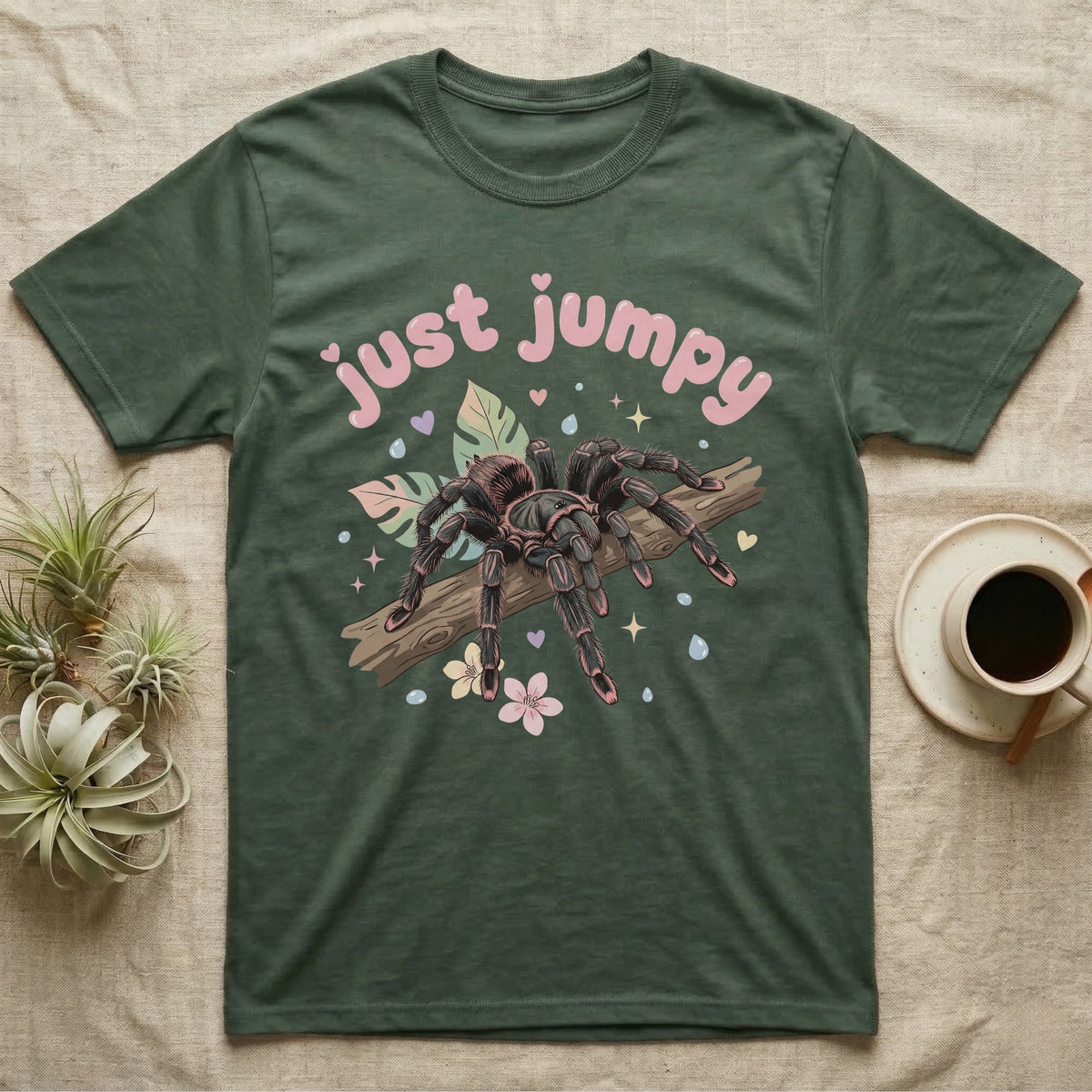 Pink Toe Tarantula Softie T-Shirt in Military Green — Pink toe tarantula poised to leap on a branch under a puffy pastel "just jumpy" bubble wordmark with tiny hearts.