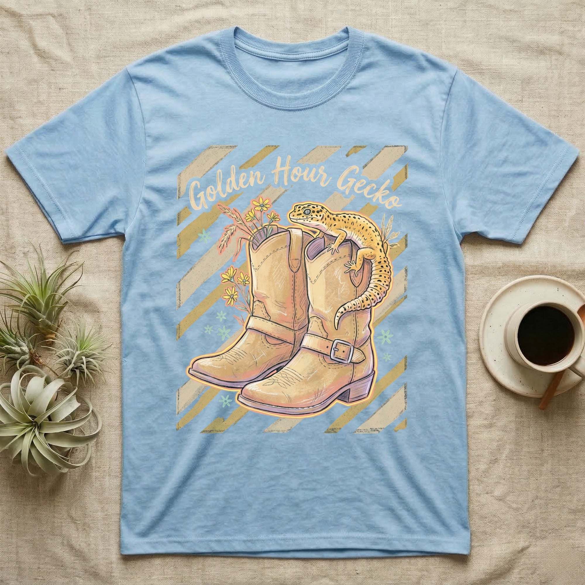 Light blue t-shirt featuring a gecko on cowboy boots and "Golden Hour Gecko" text.