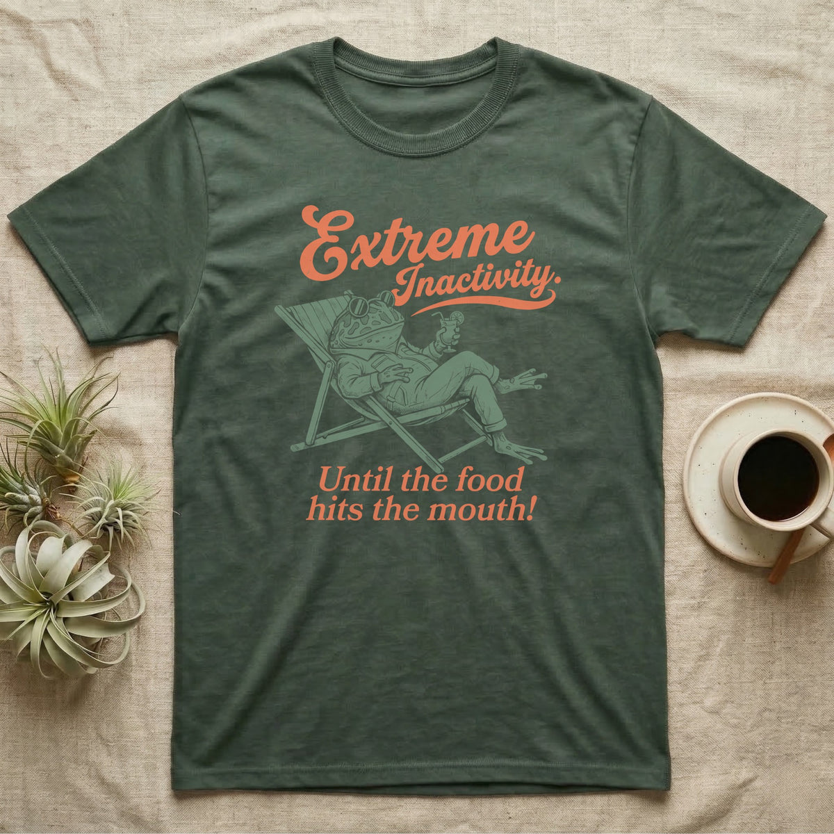 Pacman Frog Lazy Day T-Shirt in Military Green — Illustrated pacman frog reclining in a beach chair in a jacket with sunglasses and a cocktail, coral script reading Extreme Inactivity Until The Food Hits The Mouth.