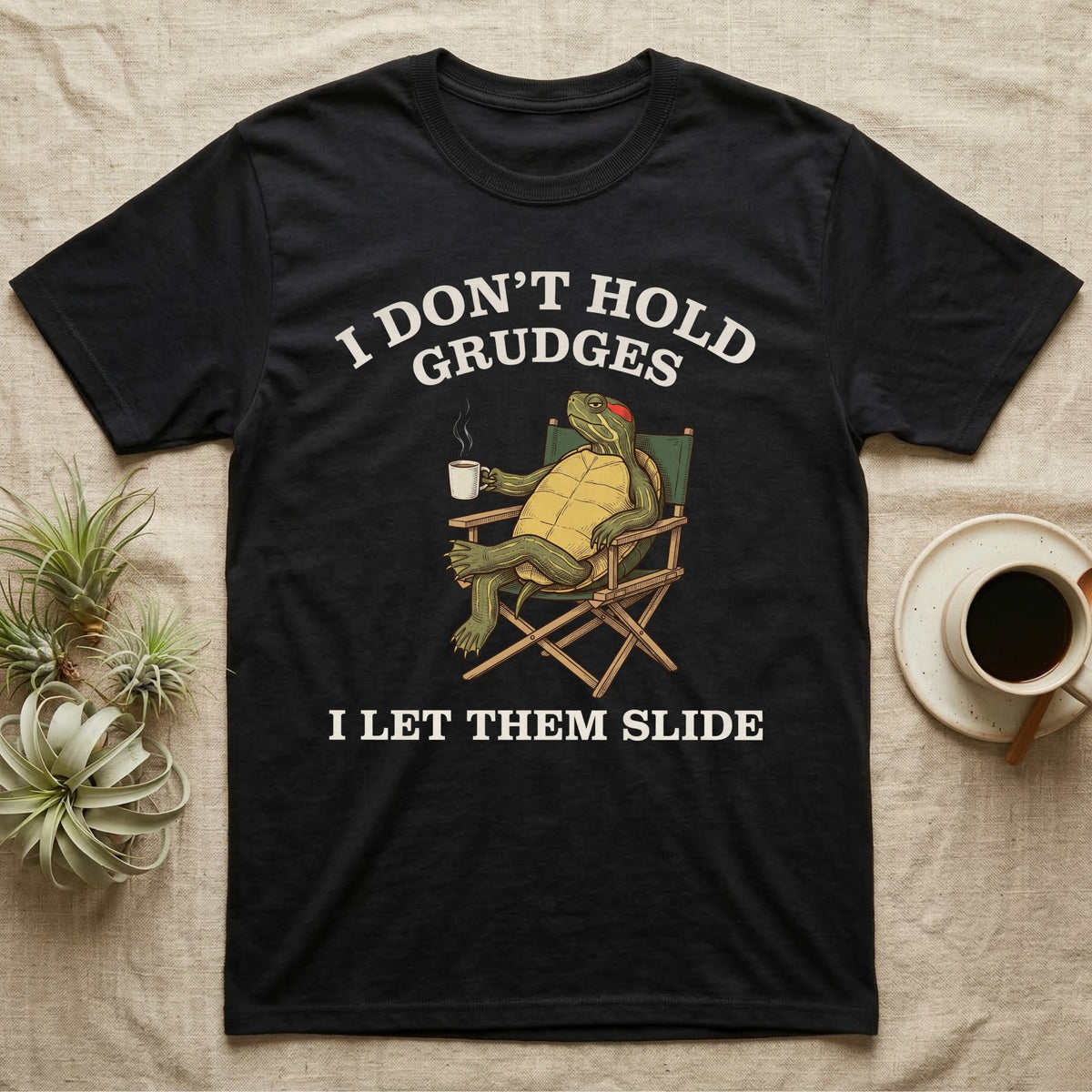 Red-Eared Slider Grudges T-Shirt in Black — Engraved red-eared slider lounging in a camp chair with tea under I Don't Hold Grudges I Let Them Slide