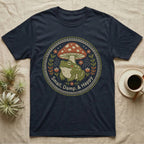 Dark t-shirt with embroidered circular design of frog, mushroom, and floral elements.