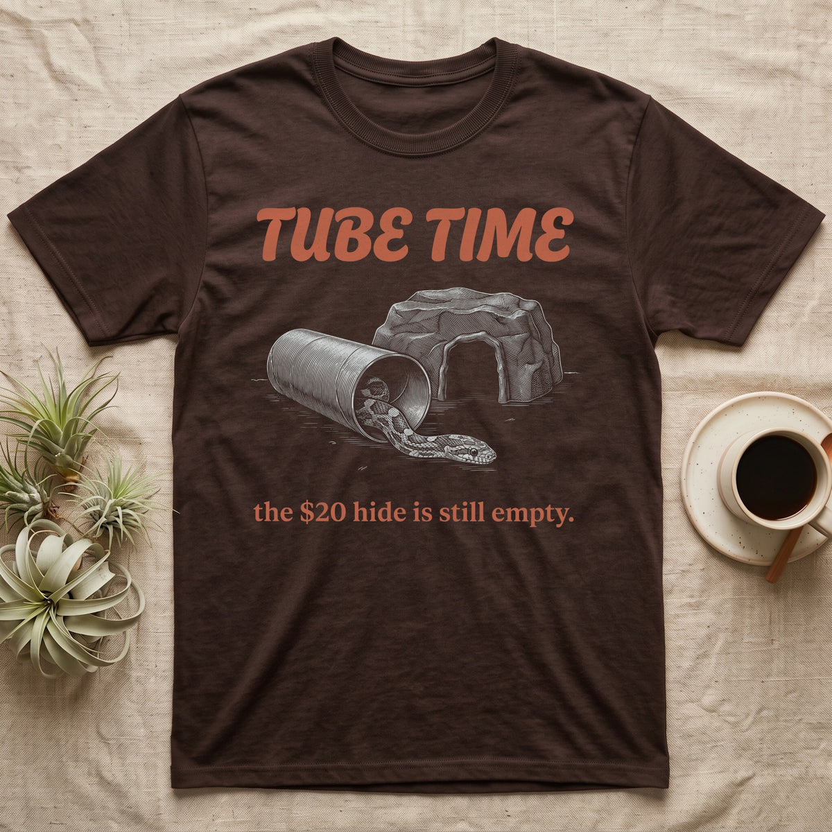 Corn Snake Tube T-Shirt in Dark Chocolate — Engraved corn snake lounging in a cardboard tube beside an empty rock hide, under retro script reading TUBE TIME.