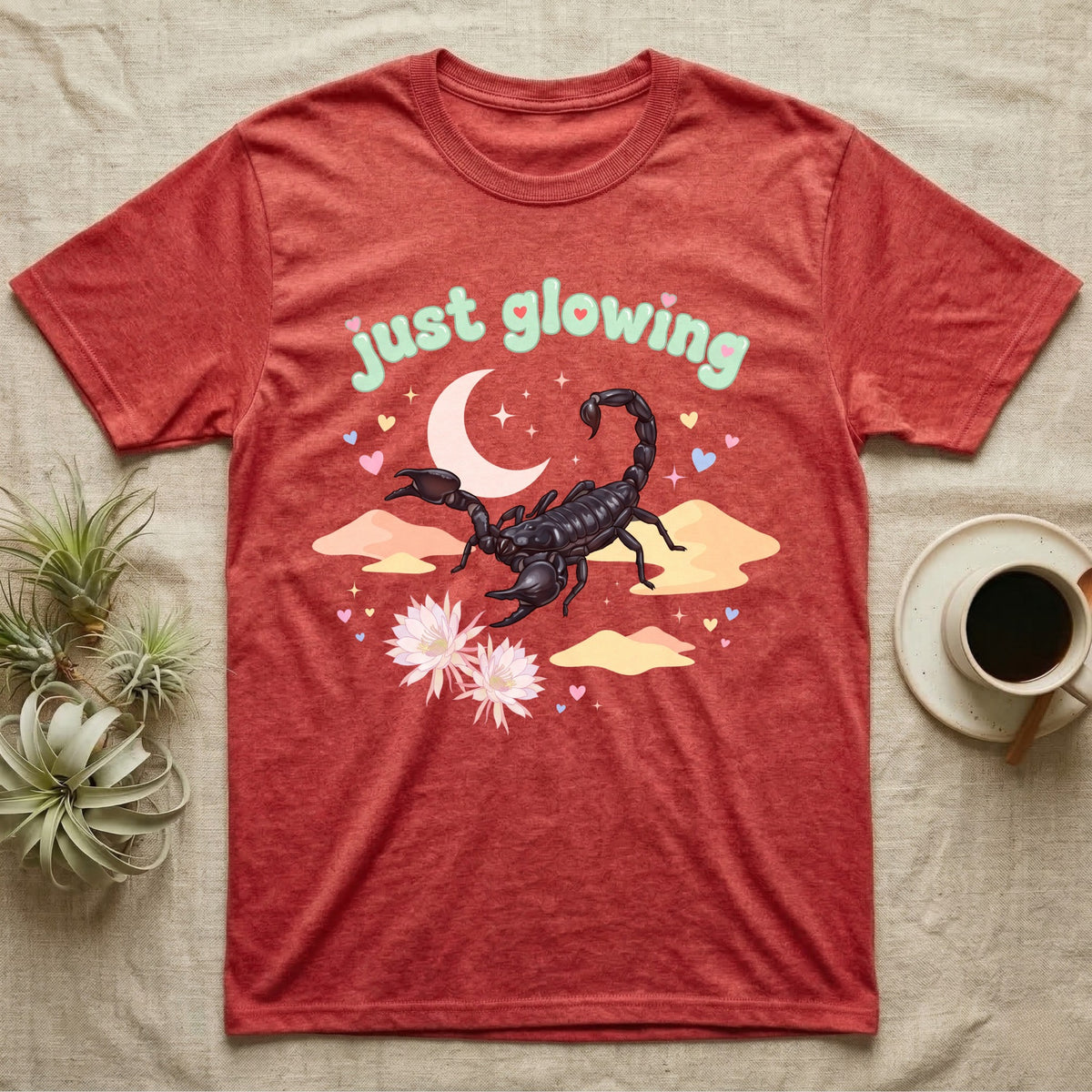 Emperor Scorpion Baby T-Shirt in Heather Red — Black emperor scorpion, pincers raised, under a pastel moon and stars with puffy mint bubble text "just glowing".