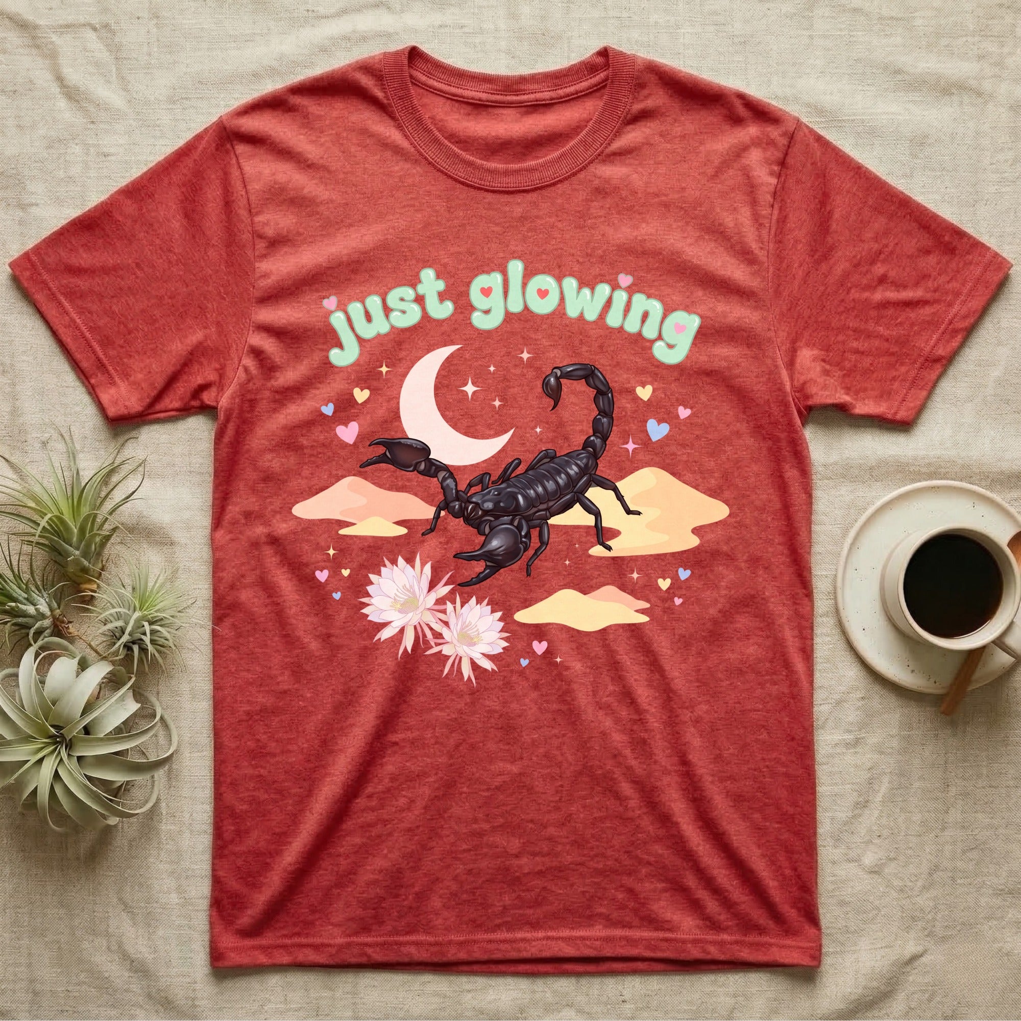 Emperor Scorpion Baby T-Shirt in Heather Red — Black emperor scorpion, pincers raised, under a pastel moon and stars with puffy mint bubble text "just glowing".