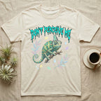 Veiled Chameleon Feral T-Shirt in Natural — Veiled chameleon on a branch with swivelling eyes under a jagged turquoise metal "DON'T PERCEIVE ME" wordmark.