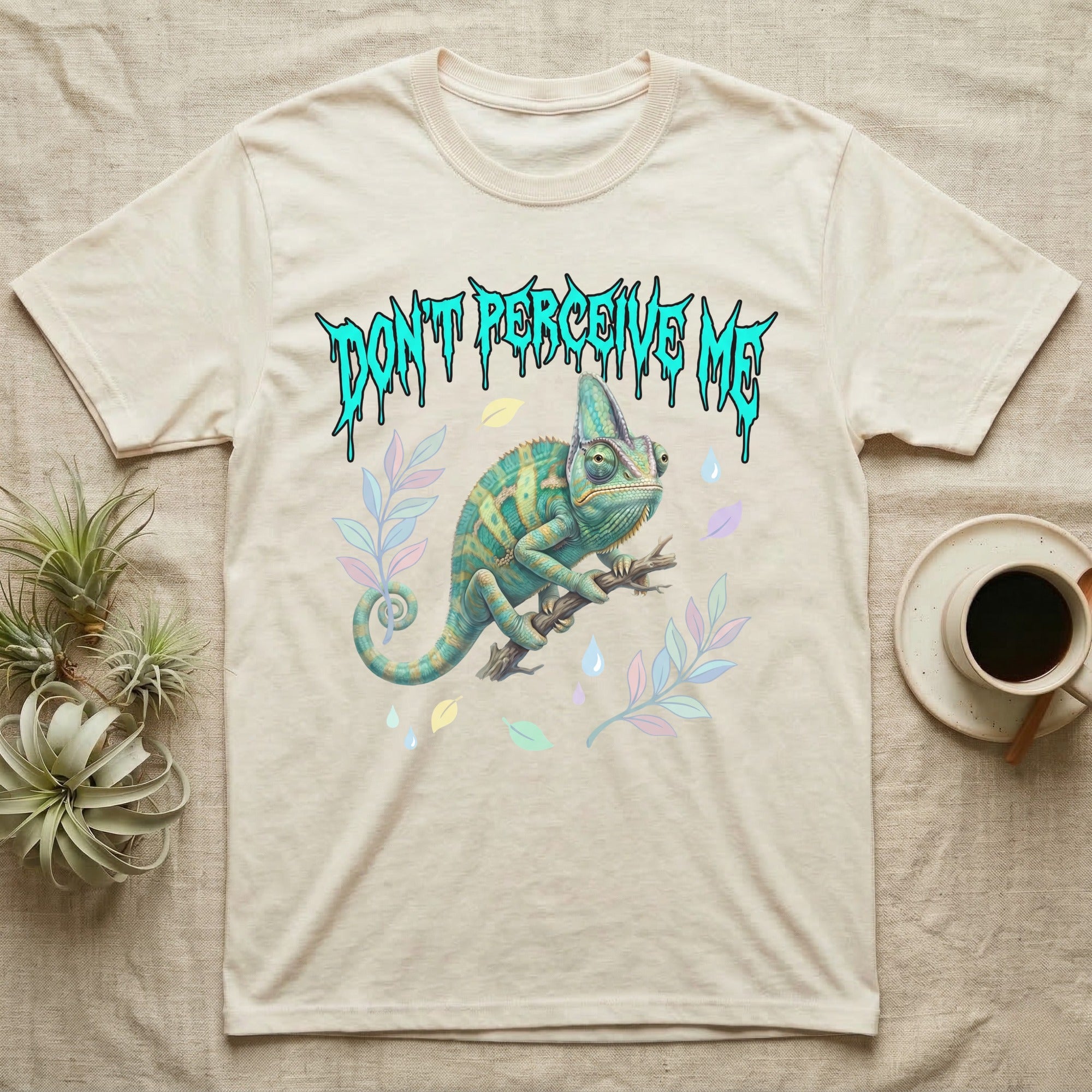 Veiled Chameleon Feral T-Shirt in Natural — Veiled chameleon on a branch with swivelling eyes under a jagged turquoise metal "DON'T PERCEIVE ME" wordmark.