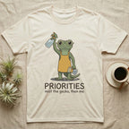 Crested Gecko Coffee T-Shirt in Natural — Storybook crested gecko standing with a raised spray mister and a pour-over coffee, text priorities below