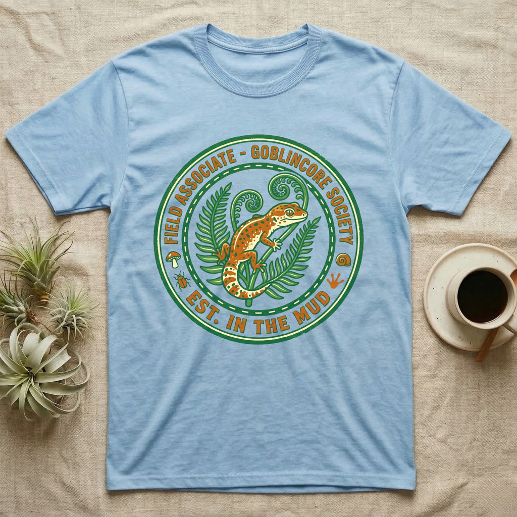 Light blue t-shirt with circular "Goblincore Society" design featuring a gecko and ferns.