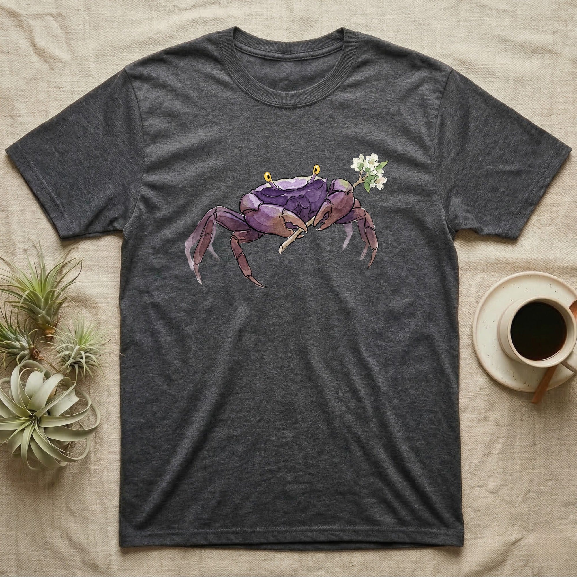 Vampire Crab Blossom T-Shirt in Dark Heather — Watercolor illustration of a violet-purple vampire crab with yellow eye stalks holding a moss-flower blossom sprig, on a dark grey t-shirt.