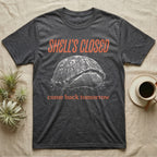 Box Turtle Shell's Closed T-Shirt in Dark Heather — Engraved white-line eastern box turtle shut tight under retro orange script reading SHELL'S CLOSED, come back tomorrow.
