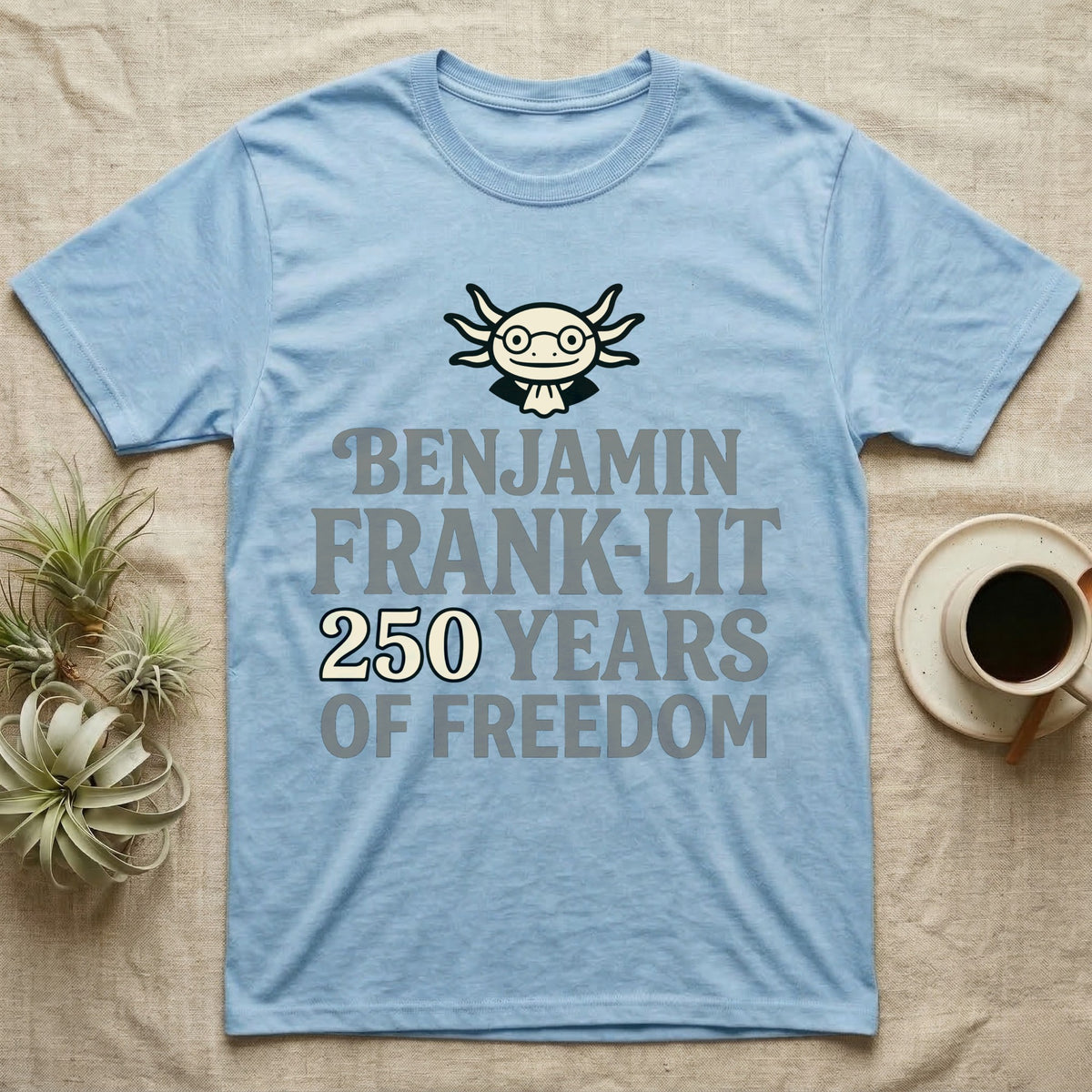 Axolotl Benjamin Franklin T-Shirt in Light Blue — Flat cream axolotl as Ben Franklin in glasses above bold text reading Benjamin Frank-Lit, 250 Years of Freedom.