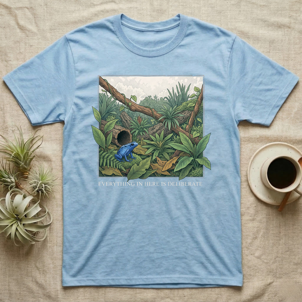 Dart Frog Bioactive Vivarium T-Shirt in Light Blue — Illustrated panel of a cobalt dart frog in a layered planted vivarium, leaves crossing the inked border.